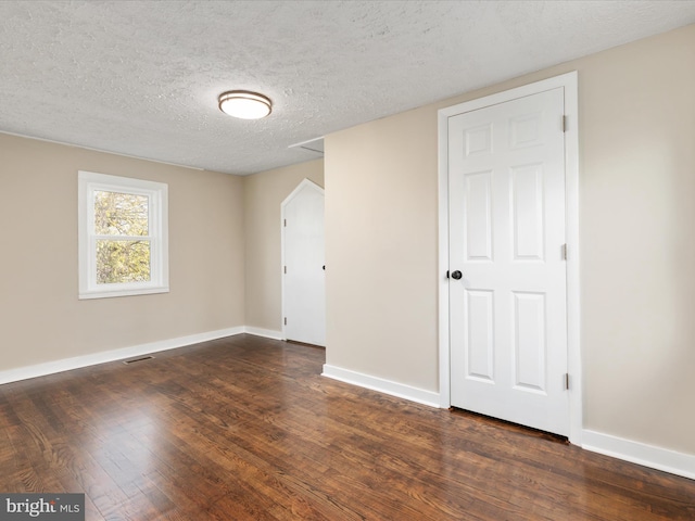 unfurnished room with dark hardwood / wood-style flooring and a textured ceiling