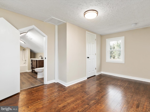 spare room featuring dark wood-type flooring and a textured ceiling