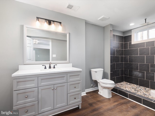 bathroom with vanity, hardwood / wood-style floors, toilet, and a tile shower