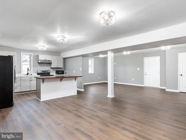 kitchen featuring a kitchen bar, sink, appliances with stainless steel finishes, dark hardwood / wood-style floors, and a kitchen island