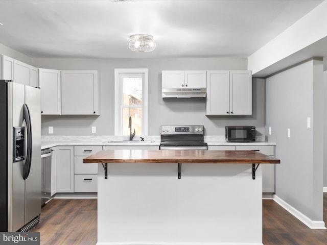 kitchen featuring stainless steel appliances, a kitchen breakfast bar, butcher block countertops, and white cabinets