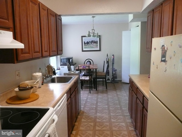 kitchen with white appliances, extractor fan, hanging light fixtures, and sink