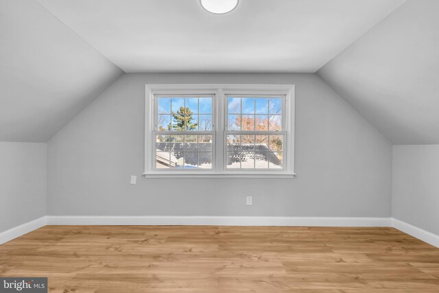 additional living space featuring vaulted ceiling and light wood-type flooring