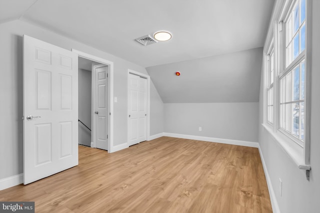 additional living space with light wood-type flooring and vaulted ceiling