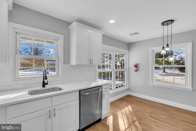 kitchen with sink, stainless steel dishwasher, light hardwood / wood-style floors, decorative light fixtures, and white cabinets