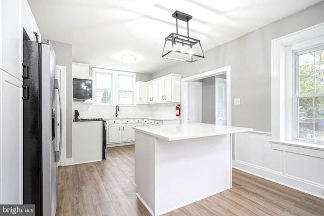 kitchen with a kitchen island, decorative light fixtures, white range with electric cooktop, stainless steel fridge with ice dispenser, and white cabinetry