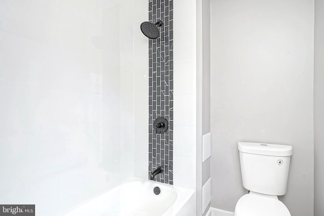 bathroom with tiled shower / bath combo and toilet