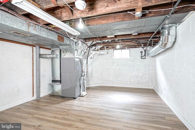 basement featuring hardwood / wood-style flooring and heating unit