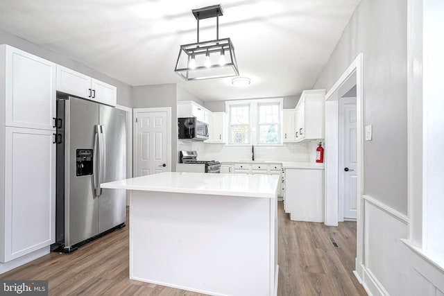 kitchen with pendant lighting, light hardwood / wood-style floors, white cabinetry, and appliances with stainless steel finishes