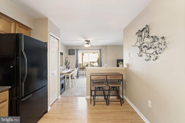 kitchen featuring black fridge, light hardwood / wood-style flooring, and ceiling fan