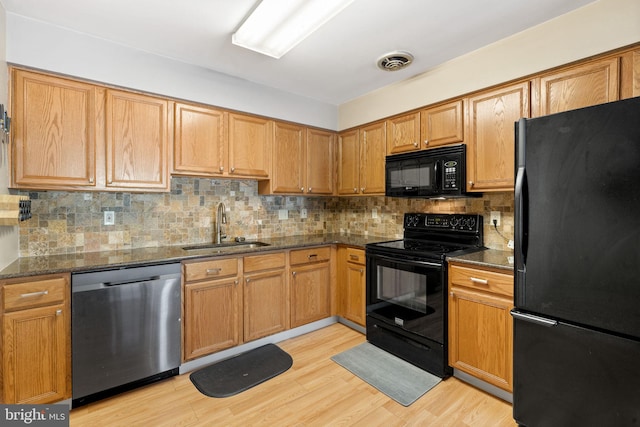 kitchen with tasteful backsplash, dark stone countertops, sink, and black appliances