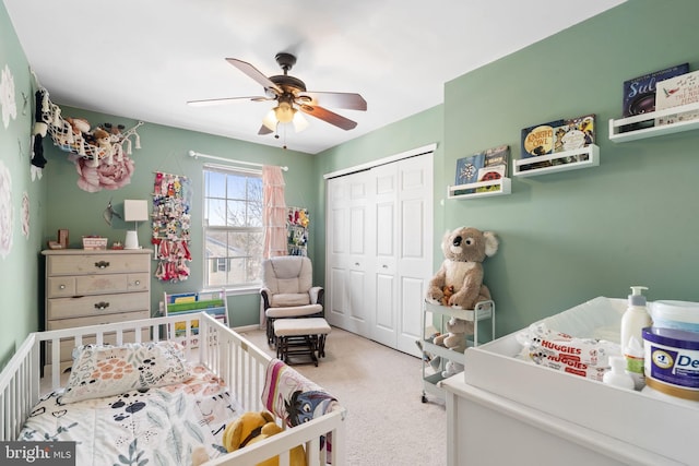 bedroom with carpet, a closet, a crib, and ceiling fan