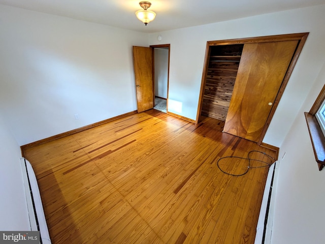 unfurnished bedroom with light hardwood / wood-style flooring, baseboard heating, and a closet