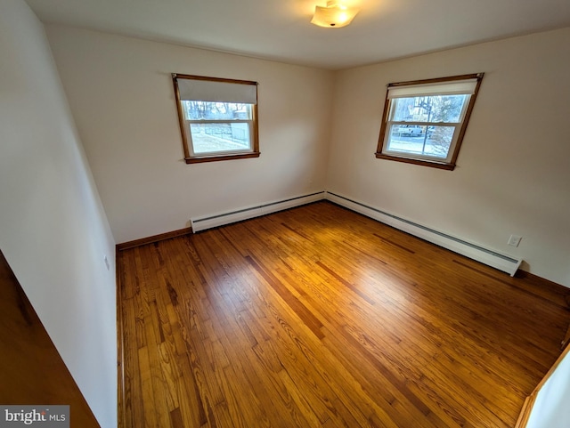 unfurnished room featuring hardwood / wood-style flooring, baseboard heating, and a wealth of natural light