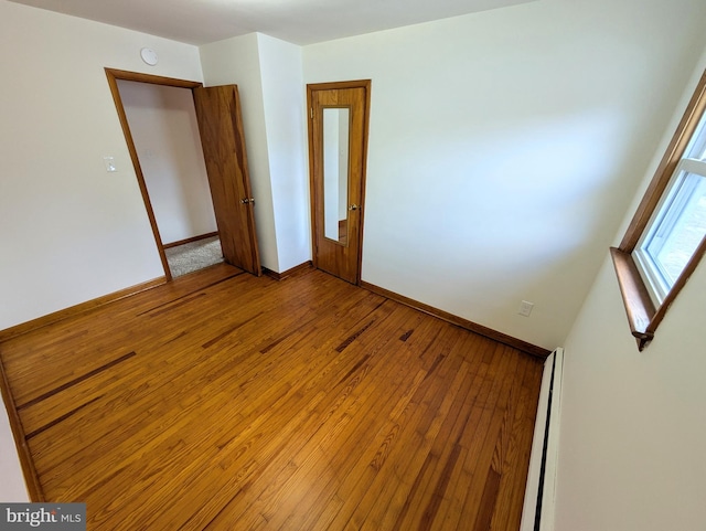 spare room featuring wood-type flooring and a baseboard heating unit