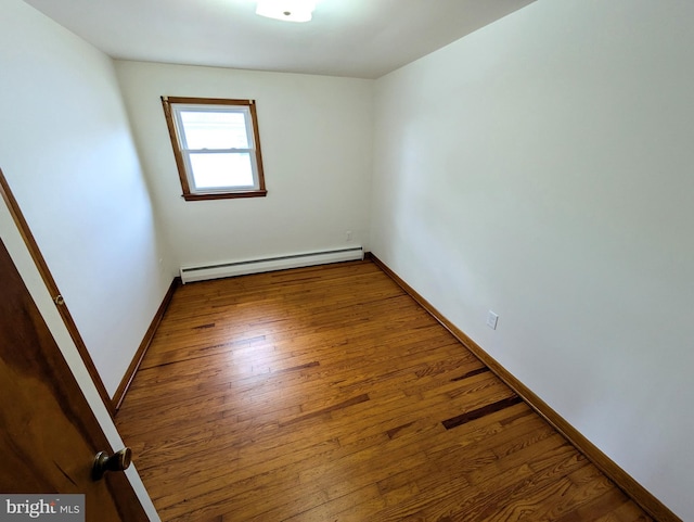 unfurnished room with wood-type flooring and baseboard heating