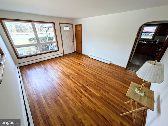 unfurnished living room featuring hardwood / wood-style flooring and baseboard heating