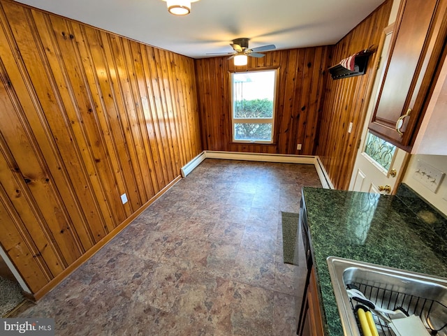 spare room featuring baseboard heating, ceiling fan, and wood walls