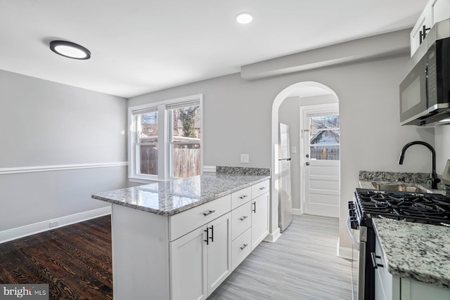 kitchen featuring light stone countertops, appliances with stainless steel finishes, light hardwood / wood-style floors, and white cabinetry