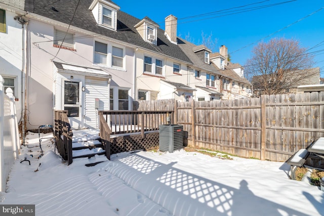 snow covered back of property with cooling unit and a deck