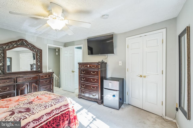 carpeted bedroom featuring ceiling fan, a closet, and a textured ceiling