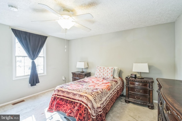 bedroom with a textured ceiling, ceiling fan, and light carpet