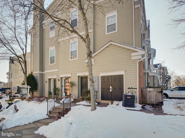 snow covered rear of property with central AC unit