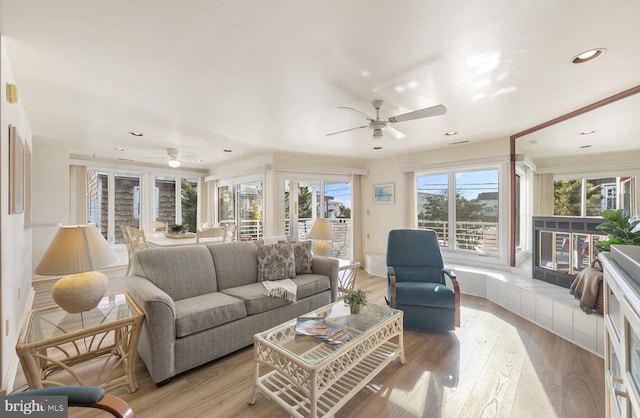 living room with a tiled fireplace and light hardwood / wood-style flooring