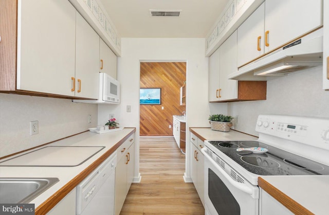 kitchen featuring white cabinets, wood walls, white appliances, and light hardwood / wood-style floors