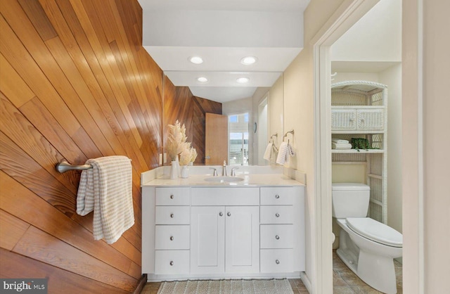 bathroom featuring vanity, toilet, and wooden walls