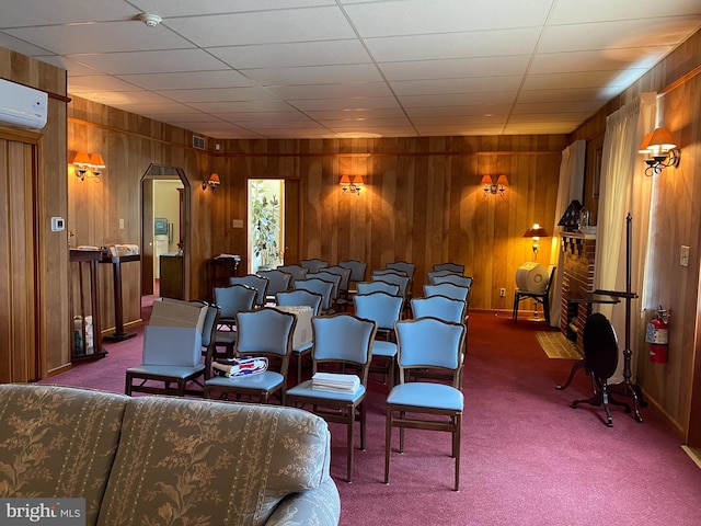 cinema room with a wall mounted air conditioner, dark carpet, and wood walls