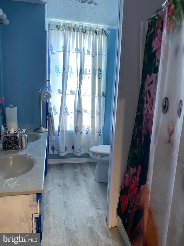 full bathroom featuring hardwood / wood-style floors, vanity, shower / tub combo, and toilet