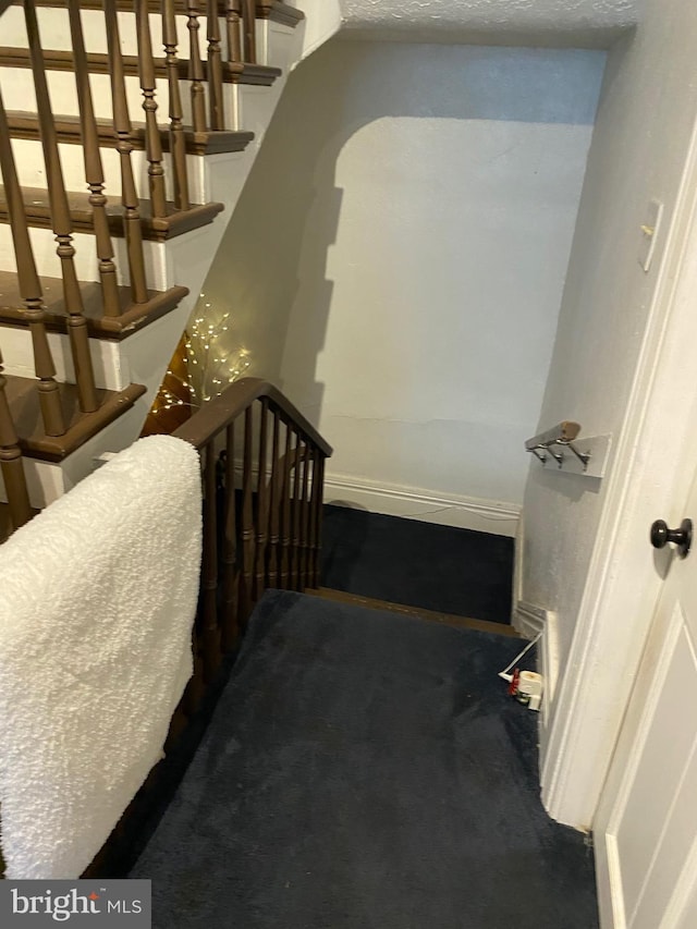 stairs featuring carpet flooring and a textured ceiling