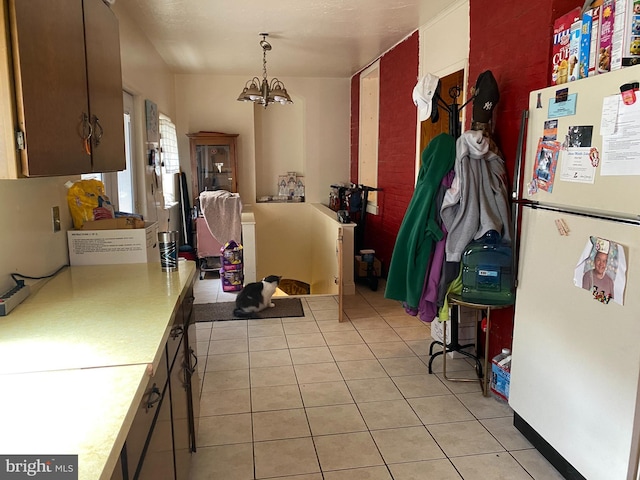 kitchen with a notable chandelier, white refrigerator, light tile patterned flooring, and hanging light fixtures