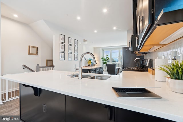 kitchen with sink, range, a kitchen breakfast bar, wood-type flooring, and kitchen peninsula