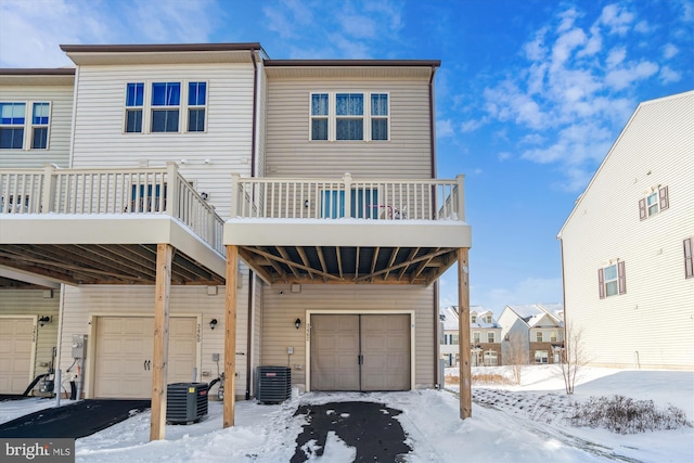 snow covered back of property with a garage and central air condition unit