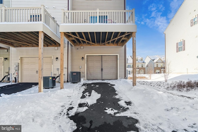 snow covered garage with central air condition unit