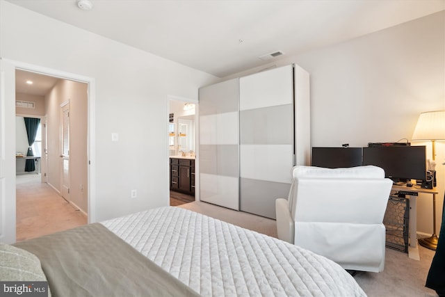 bedroom with light carpet and ensuite bath