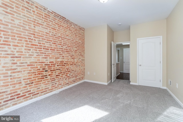 spare room with light carpet and brick wall