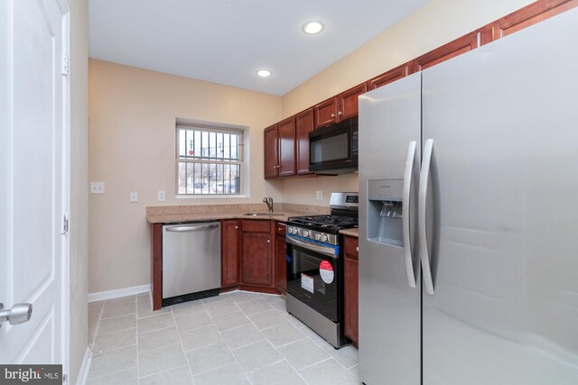 kitchen with stainless steel appliances, light stone countertops, sink, and light tile patterned floors