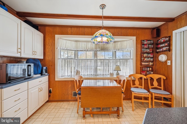 dining room featuring wood walls and beamed ceiling