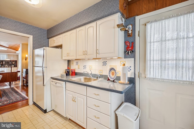 kitchen featuring sink, backsplash, white appliances, and white cabinetry