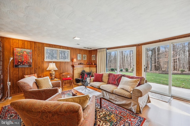 living room featuring a brick fireplace and wooden walls