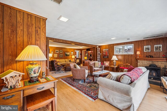 living room featuring a wood stove, light hardwood / wood-style flooring, and wood walls