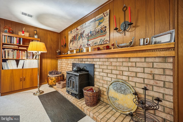 interior details with a wood stove, wood walls, ornamental molding, and carpet floors