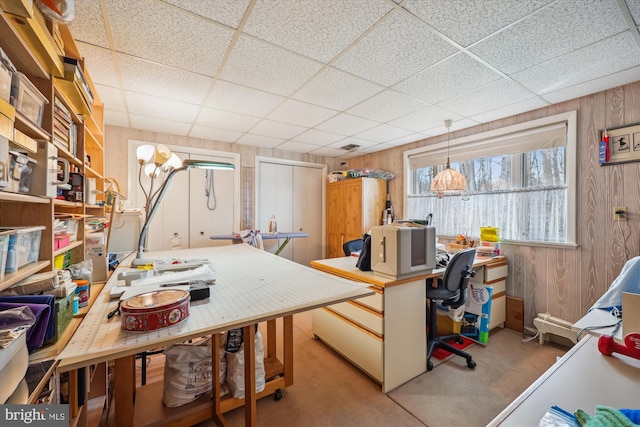 carpeted office space featuring wood walls and a drop ceiling