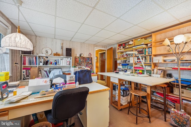 office featuring a paneled ceiling and wooden walls