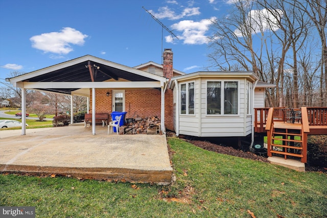 back of house featuring a wooden deck, a patio area, and a lawn