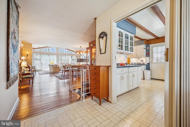 kitchen featuring pendant lighting, backsplash, white cabinetry, and a healthy amount of sunlight