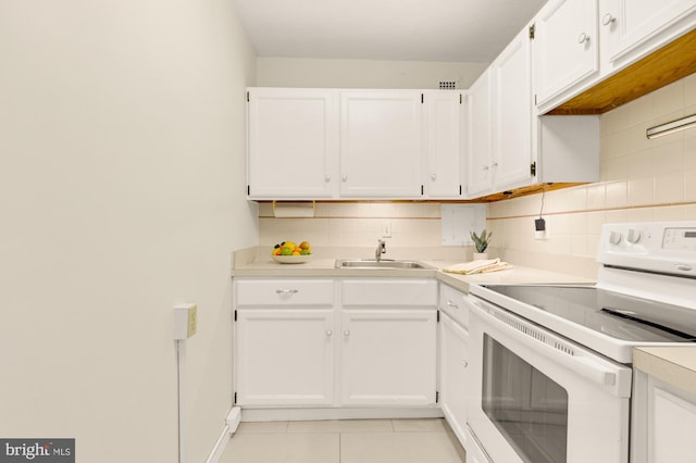 kitchen featuring backsplash, white range with electric stovetop, sink, light tile patterned floors, and white cabinets